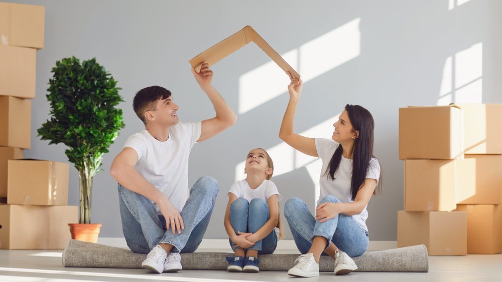 A family holding a cut out roof over their home